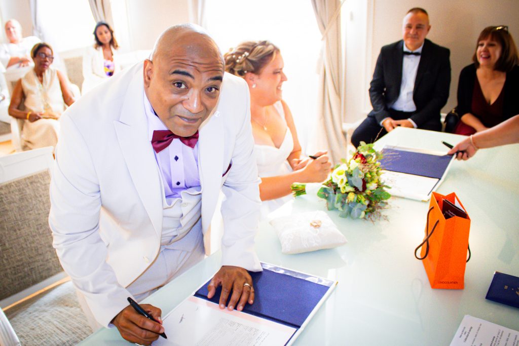 Moment de signature lors d’une cérémonie de mariage civil, entouré des proches.