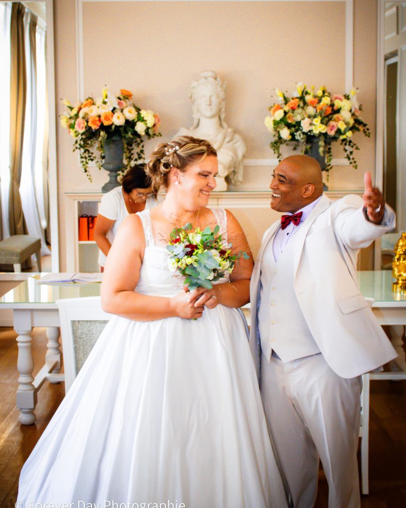 Mariés souriants à la fin de la cérémonie civile, célébrant leur union dans une salle décorée.