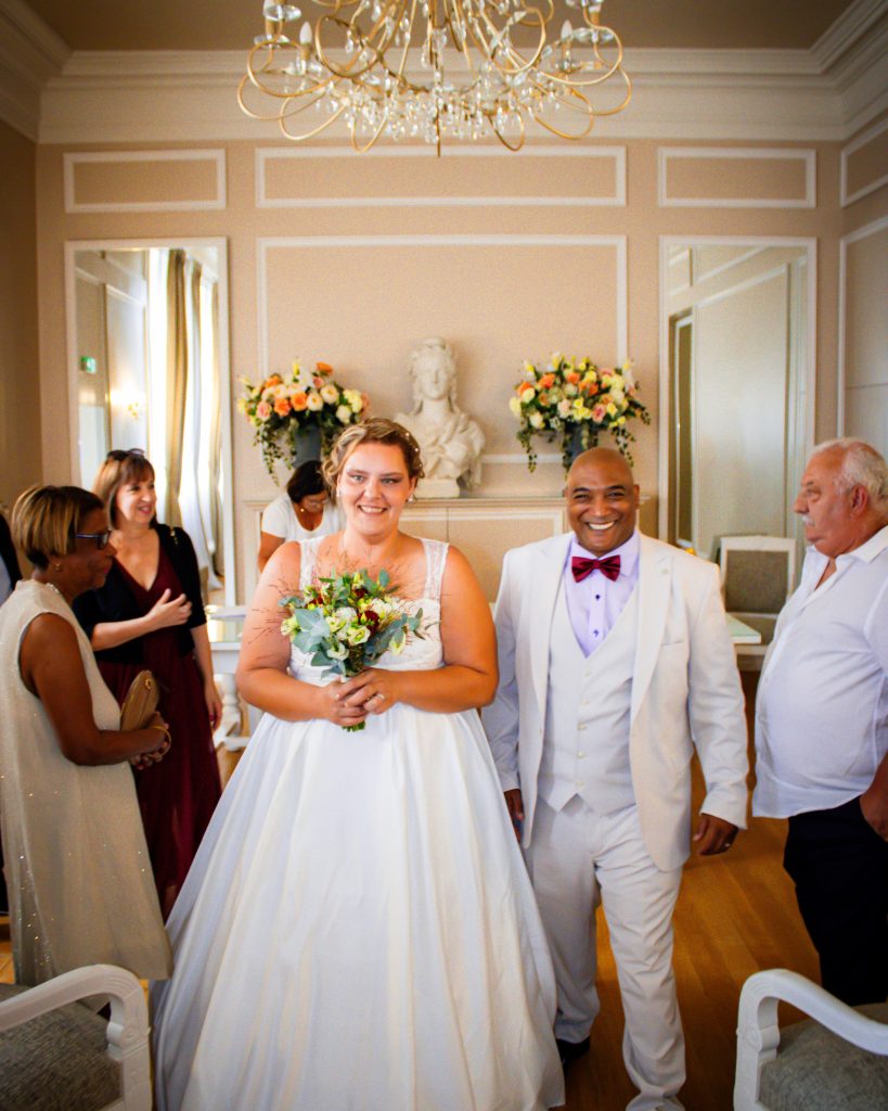 Mariés souriants entourés de leurs proches à la sortie de la cérémonie civile.