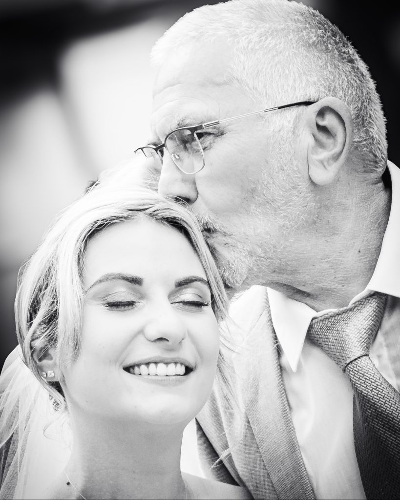 Moment tendre entre un proche et la mariée, exprimant affection et émotion le jour du mariage.