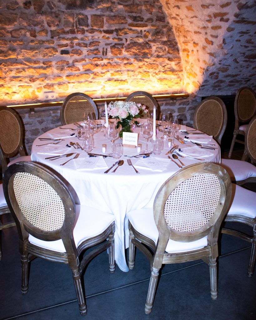 Table de réception élégante décorée pour un mariage, avec chaises vintage et lumière tamisée.