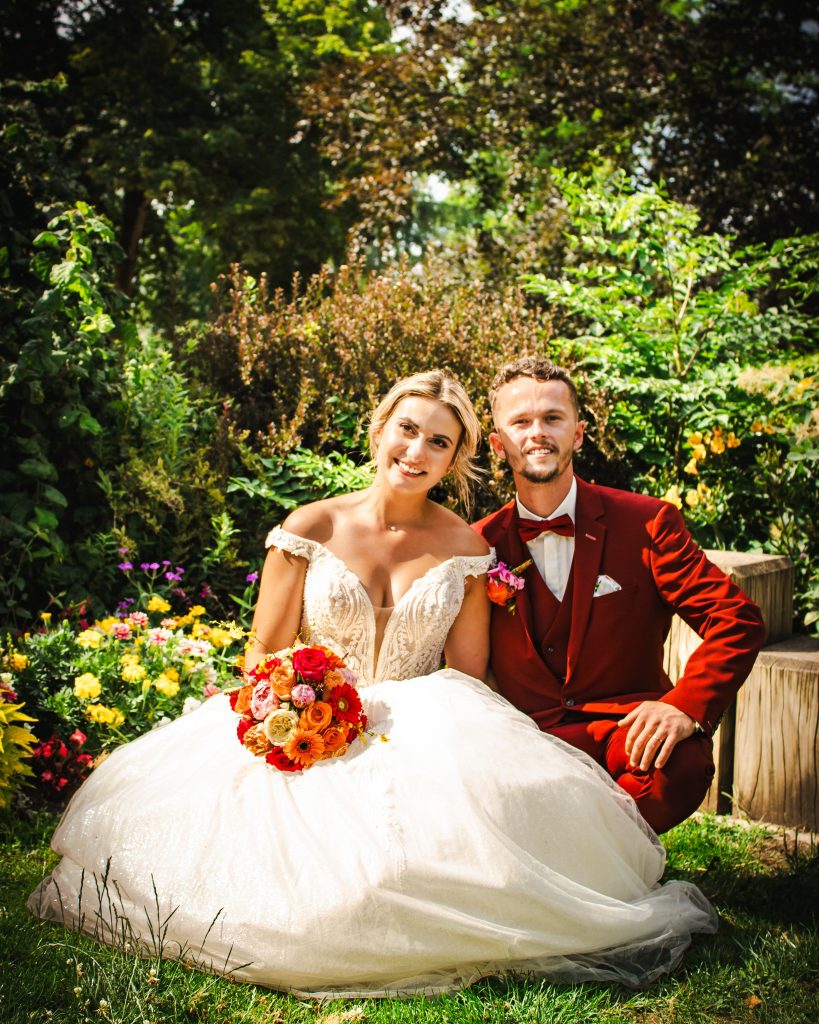 Couple de mariés posant dans un jardin fleuri lors de leur séance photo de mariage.