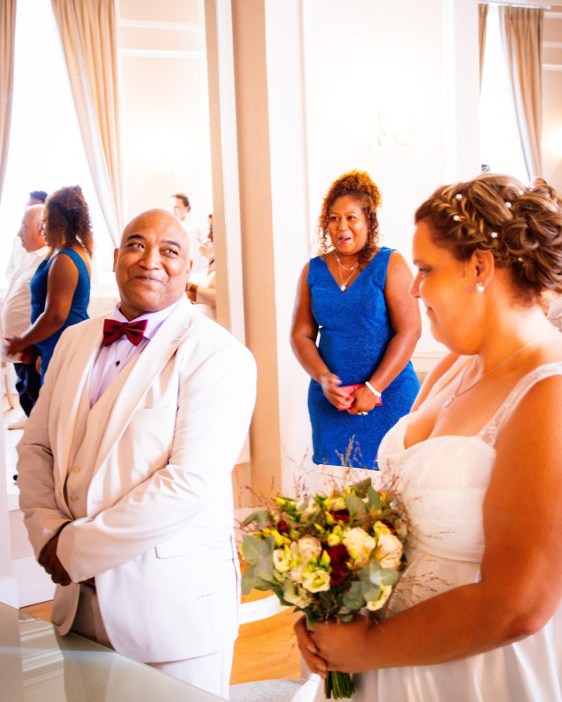 Moment de cérémonie de mariage civil avec les mariés se faisant face, entourés de leurs proches.