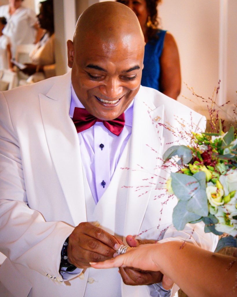 Marié souriant en costume clair lors de l’échange des alliances.