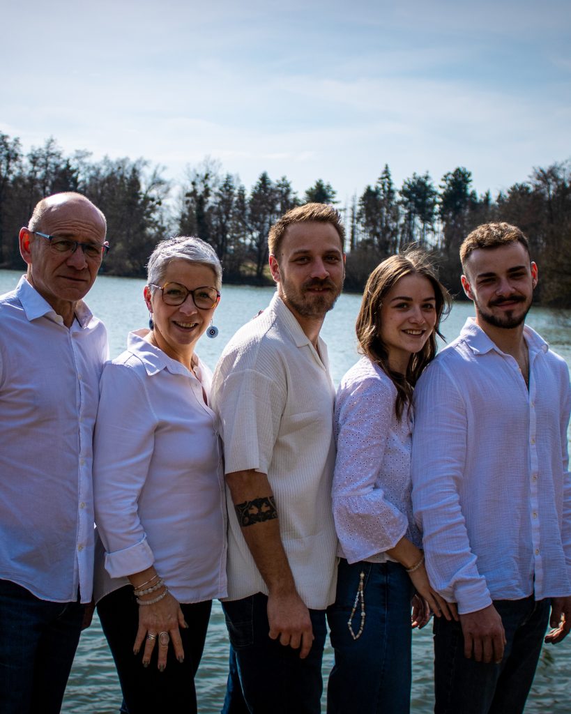 Famille posant ensemble au bord d’un lac lors d’une séance photo en extérieur.