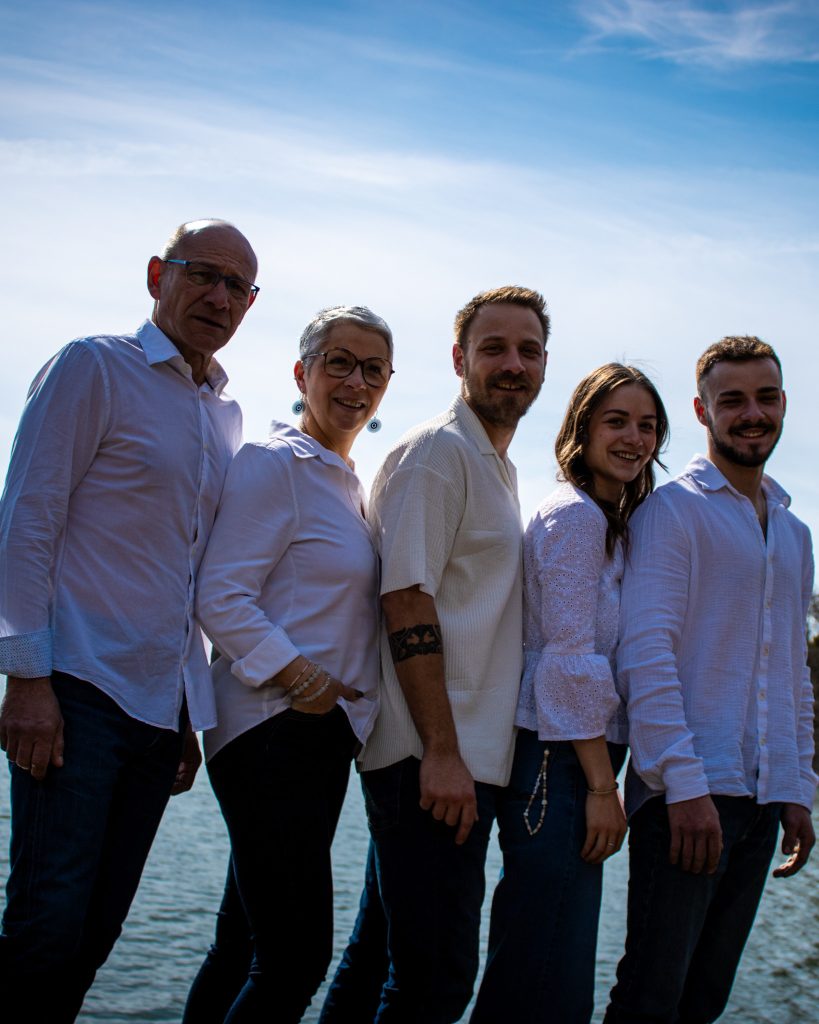 Famille alignée en extérieur au bord de l’eau, posant ensemble lors d’une séance photo.