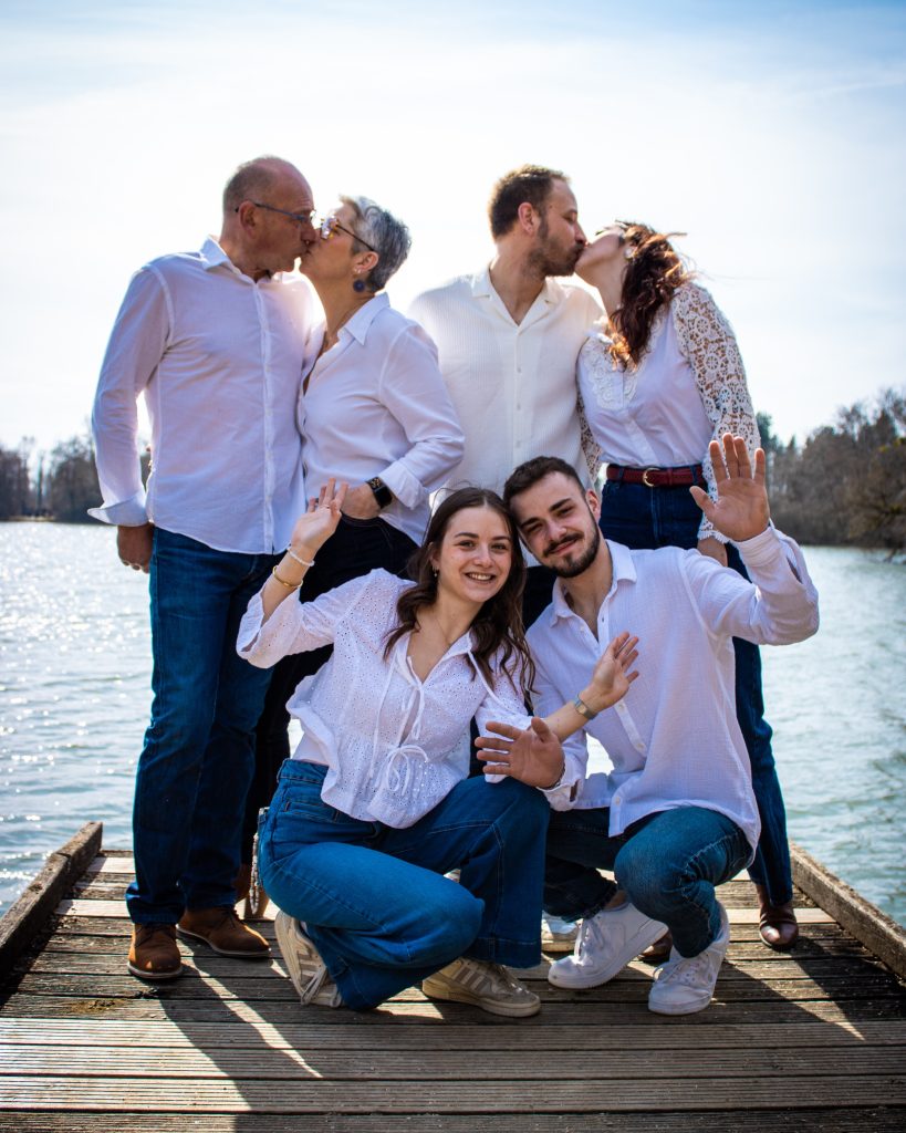 Photo de famille en extérieur sur un ponton, montrant un groupe souriant et complice.