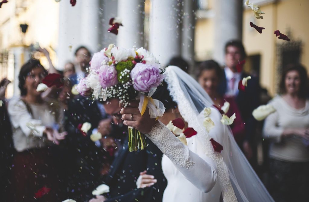Sortie de cérémonie de mariage avec une mariée recevant des pétales de fleurs lancés par les invités.